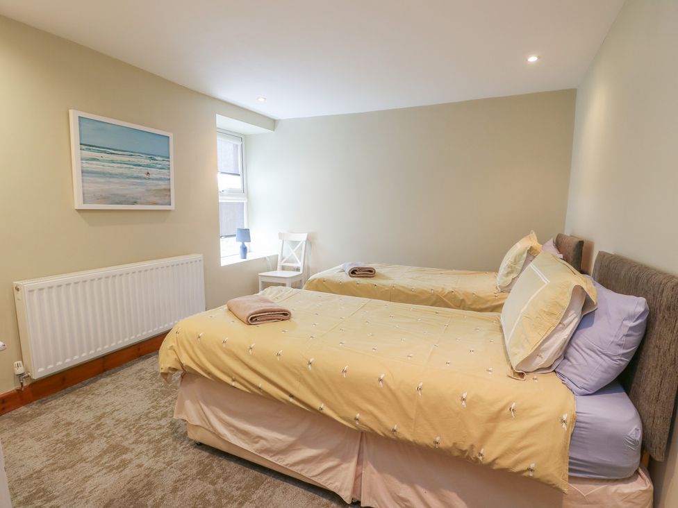 A bedroom with two single beds and a chair at Chapel House Elim near Llanddeusant