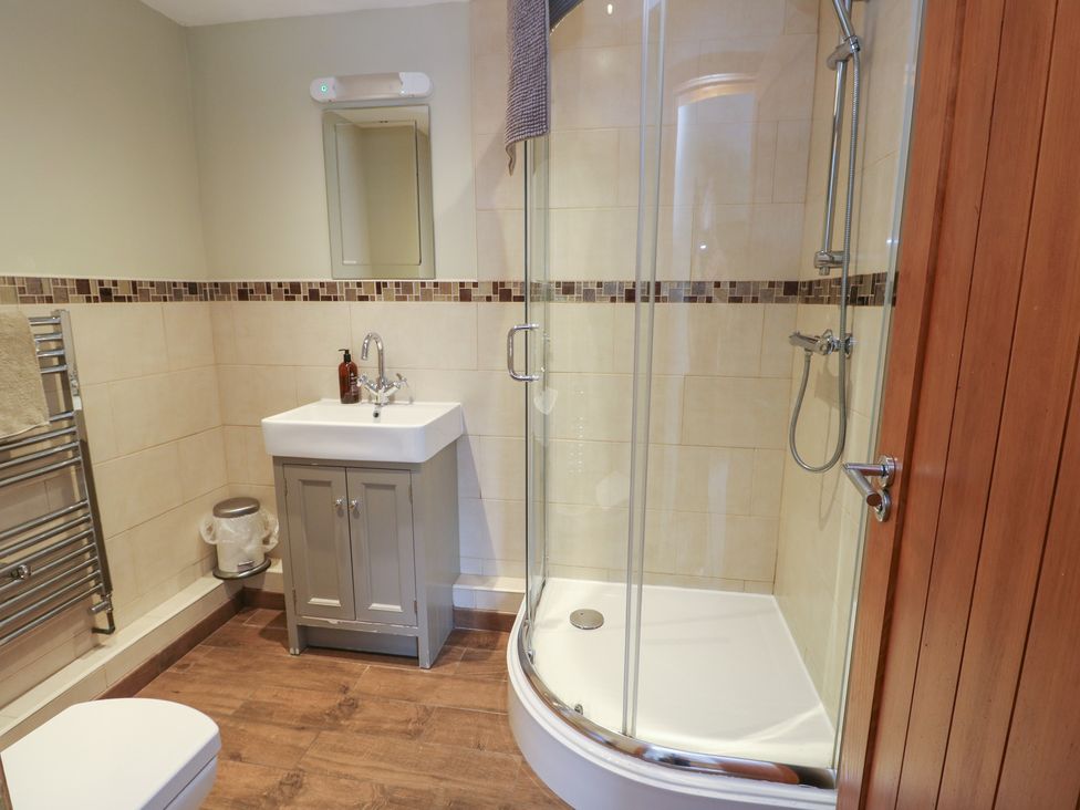 A bathroom with a shower, sink, and towel radiator at Chapel House Elim near Llanddeusant