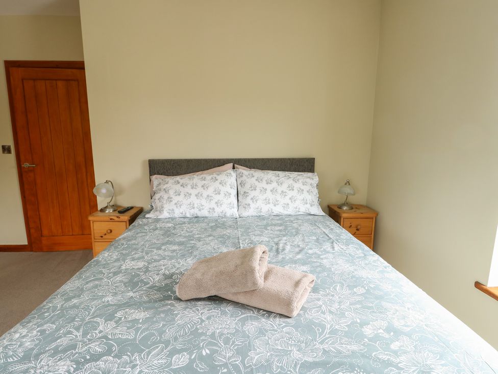 A bedroom with a bed and nightstands at Chapel House Elim near Llanddeusant