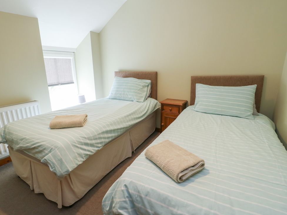 A bedroom with two single beds and a bedside table at Chapel House Elim near Llanddeusant