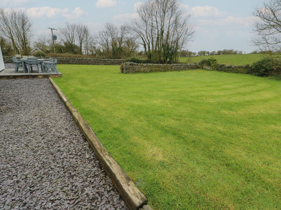 A garden with grass, a table, and chairs at Chapel House Elim near Llanddeusant