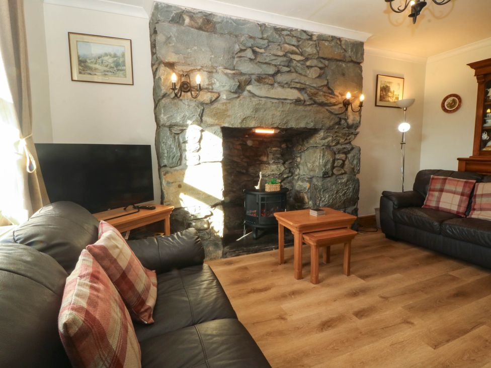 A living room with a sofa, television, and fireplace at Tyddyn in Dyffryn Ardudwy
