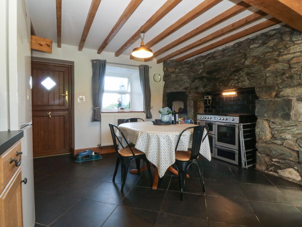 A kitchen with a dining table and stove at Tyddyn in Dyffryn Ardudwy