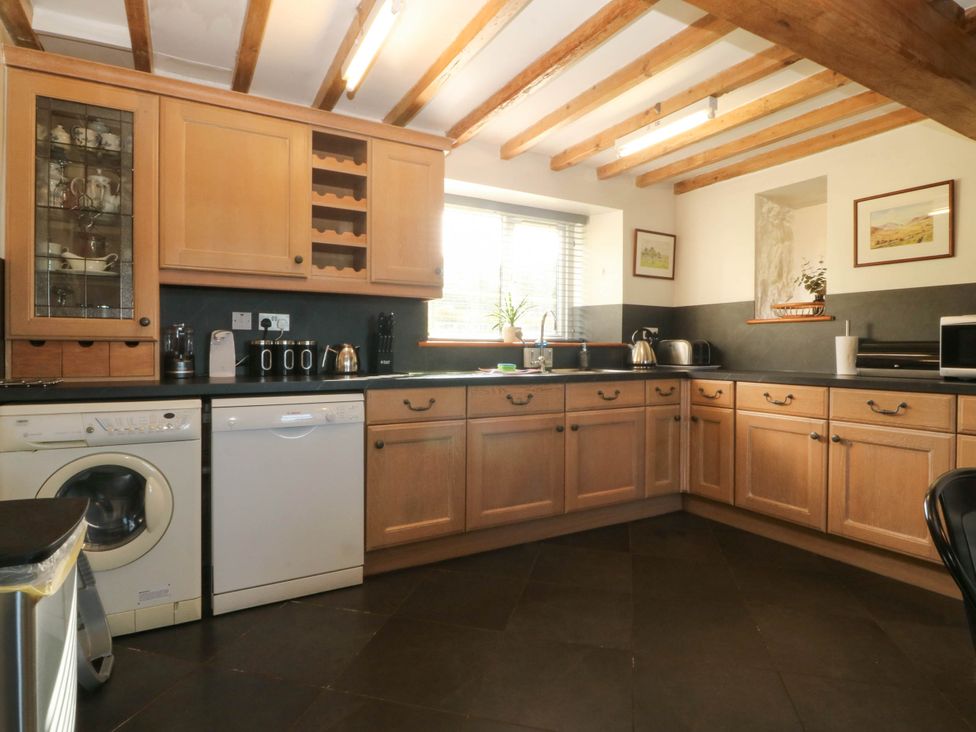 A kitchen with wooden cupboards and appliances at Tyddyn in Dyffryn Ardudwy