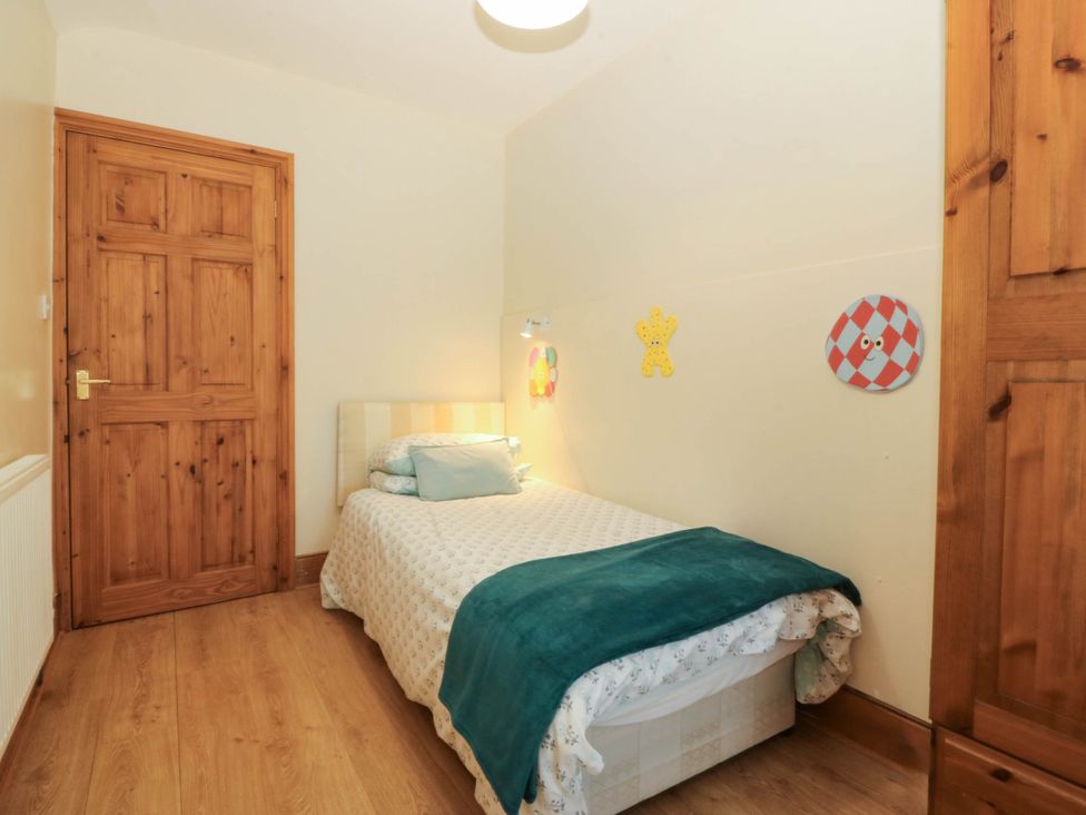 A bedroom with a single bed and wooden door at Tyddyn Dyffryn Ardudwy