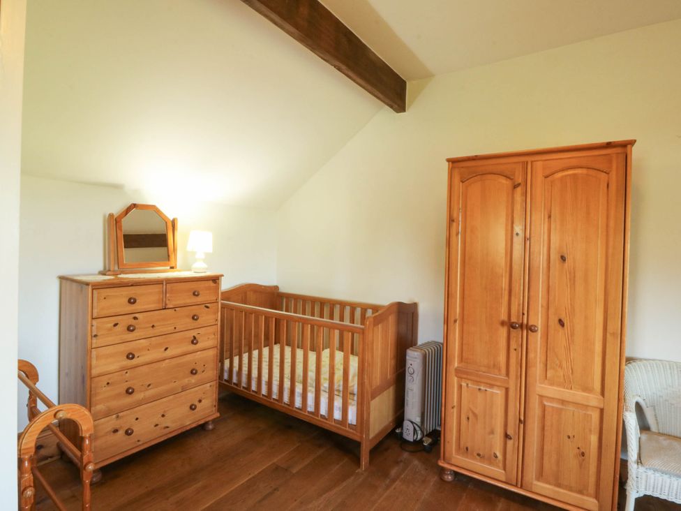 A bedroom with a crib and a dresser at Tyddyn in Dyffryn Ardudwy