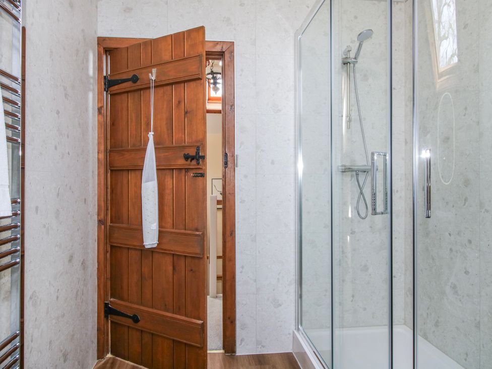 A bathroom with a shower and wooden door at The Wain House in Westhope near Church Stretton