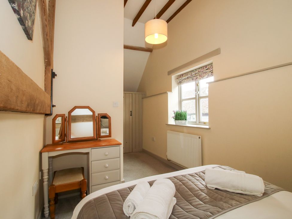 A bedroom with a bed and a desk with a mirror at The Wain House in Westhope near Church Stretton