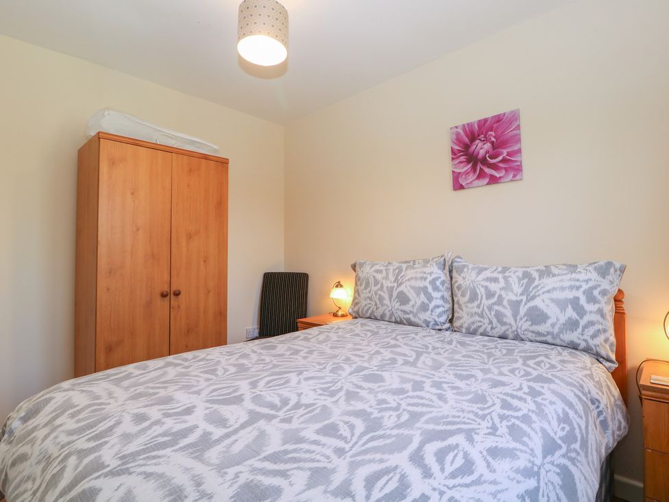 A bedroom with bed, wardrobe, lamp and artwork at The Turbles - Swallows Nest Castlemorton near Welland