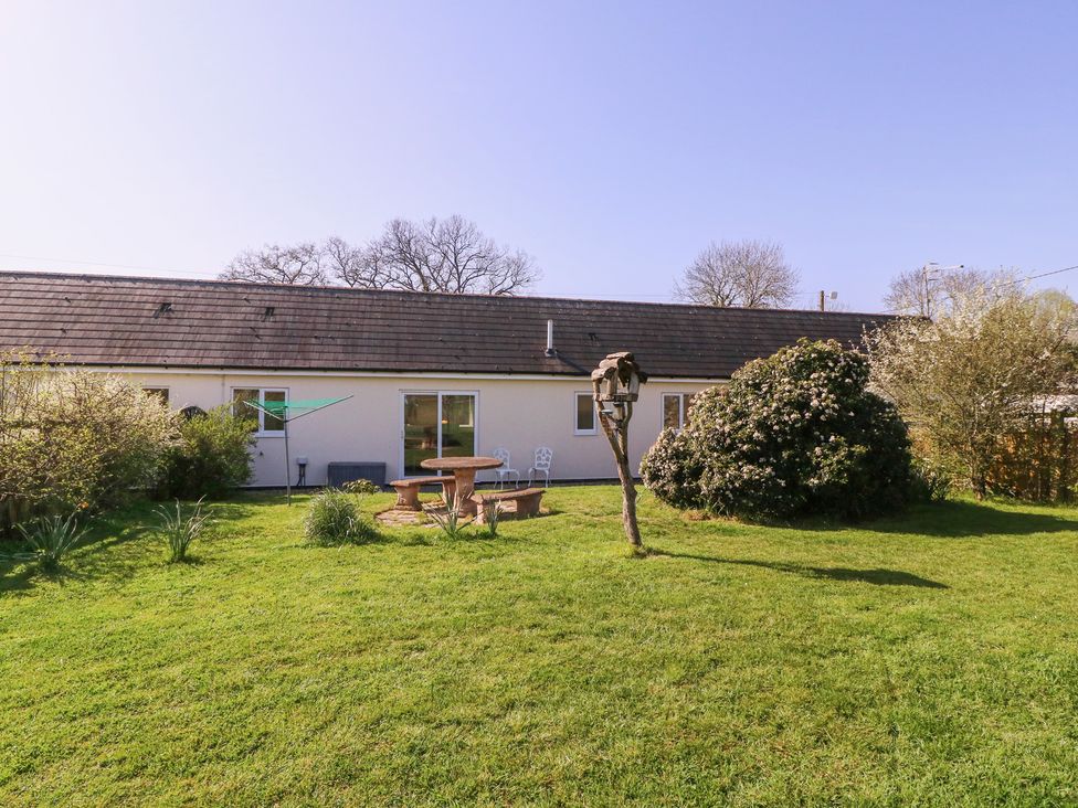 A garden with a table and chairs in front of a house at The Turbles - Swallows Nest Castlemorton near Welland