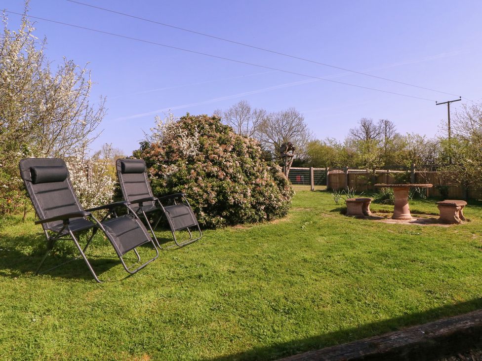 A garden with chairs and a birdbath at The Turbles - Swallows Nest in Castlemorton near Welland