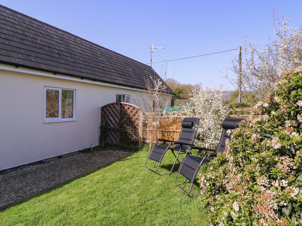 A garden with chairs and a gate at The Turbles - Swallows Nest Castlemorton near Welland
