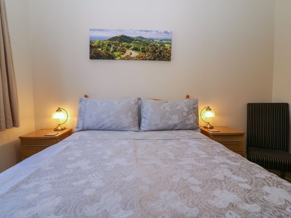 A bedroom with a bed and bedside lamp at The Turbles - Wagtail in Castlemorton near Welland