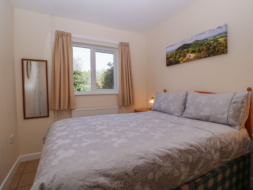 A bedroom with a bed, mirror, and window at The Turbles - Wagtail in Castlemorton near Welland