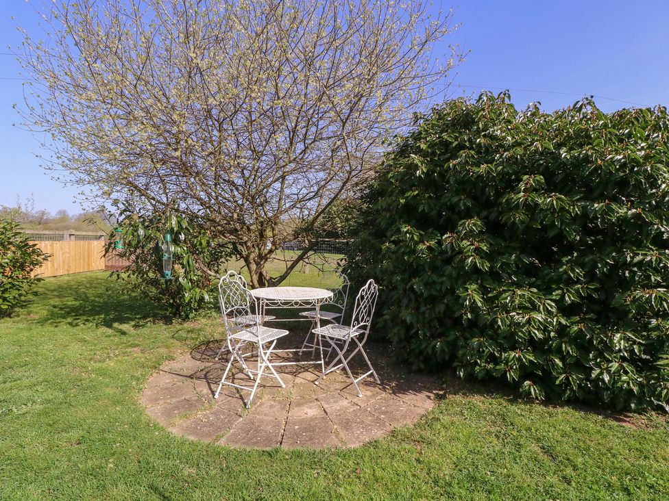 A garden with a table and chairs under a tree at The Turbles - Wagtail in Castlemorton near Welland