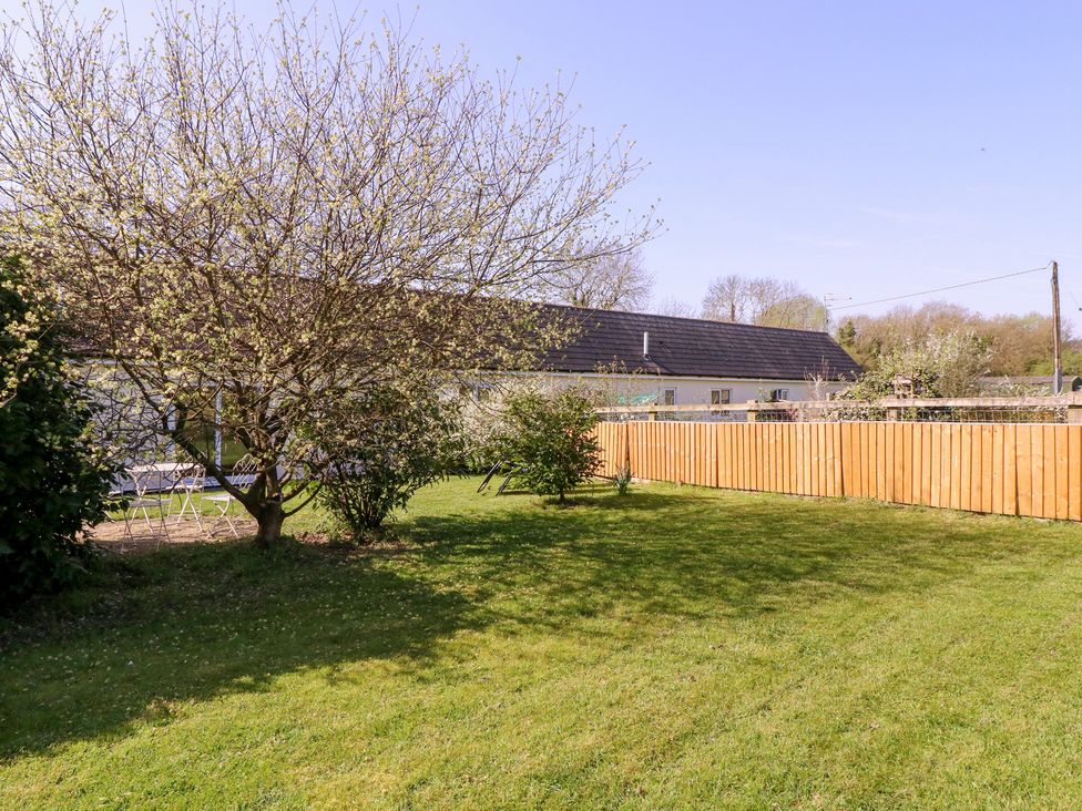 A garden area with grass, a tree, chairs, and a fenced boundary at The Turbles - Wagtail in Castlemorton near Welland