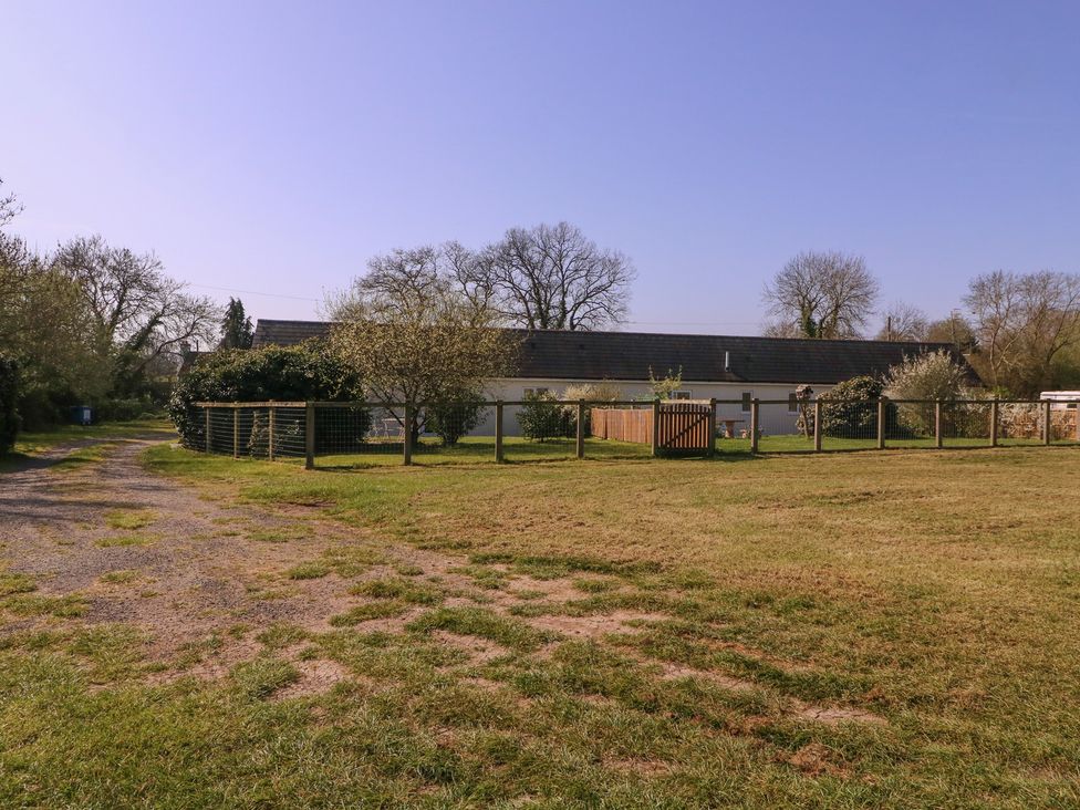 A house surrounded by a fence and trees at The Turbles - Wagtail Castlemorton near Welland