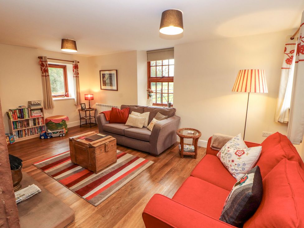 A living room with a sofa, armchair, and bookshelf at The Old Bothy Bolton Low Houses near Wigton