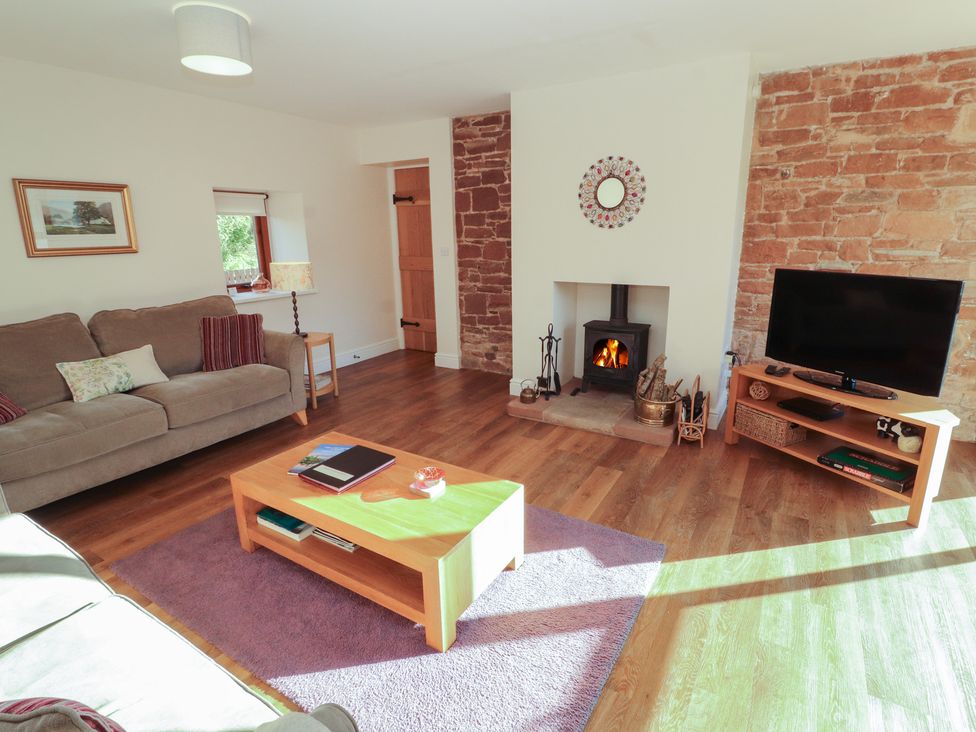 A living room with a sofa and a fireplace at The Old Grainstore Bolton Low Houses near Wigton