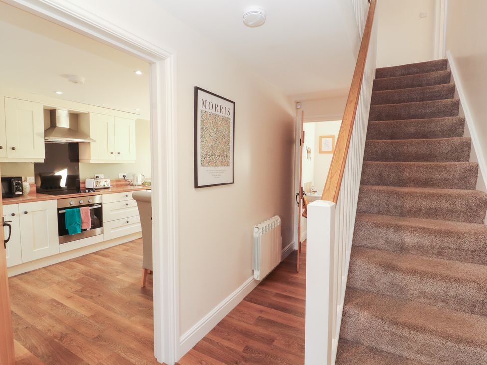 A hallway with a staircase and a view into the kitchen at The Old Grainstore Bolton Low Houses near Wigton