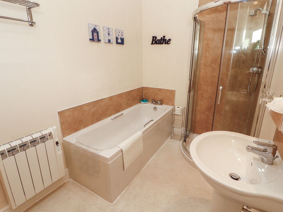 A bathroom with a bathtub, shower and sink at The Old Grainstore Bolton Low Houses near Wigton