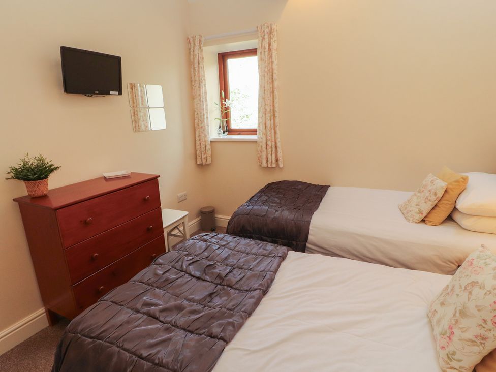 A bedroom with two single beds and a dresser at The Old Grainstore Bolton Low Houses near Wigton