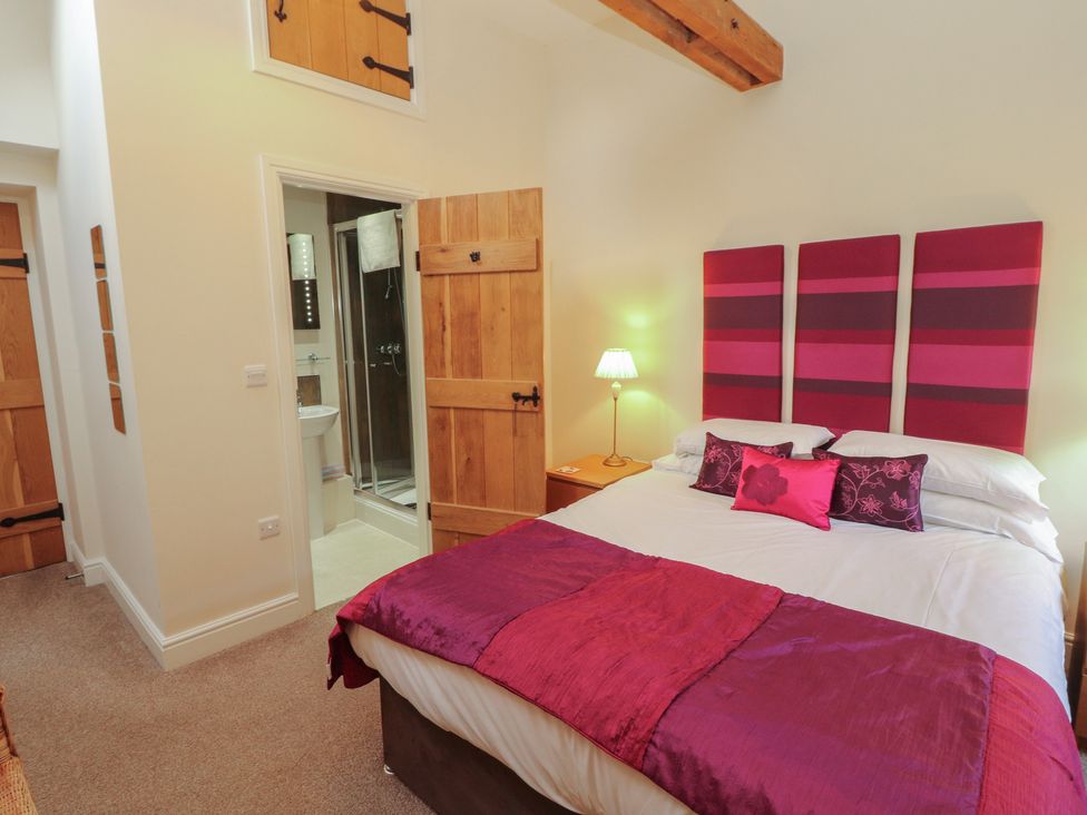 A bedroom with a bed and mirrored bathroom at The Old Grainstore Bolton Low Houses near Wigton
