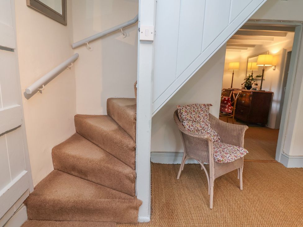 A hallway with stairs and a chair at Wolvesacre Mill Cottage Agden near Whitchurch