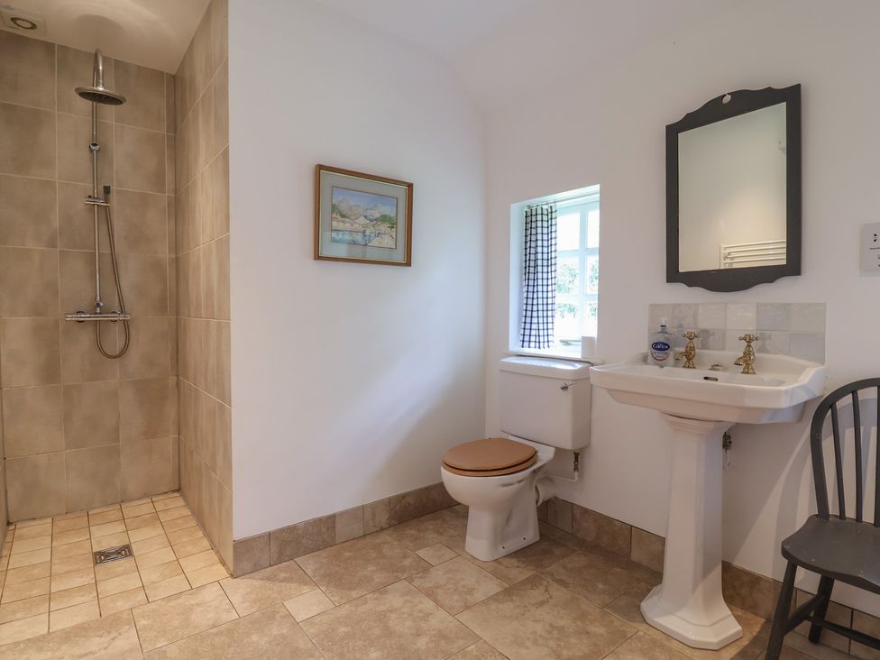 A bathroom with a shower, toilet, sink, and chair at Wolvesacre Mill Cottage in Agden near Whitchurch