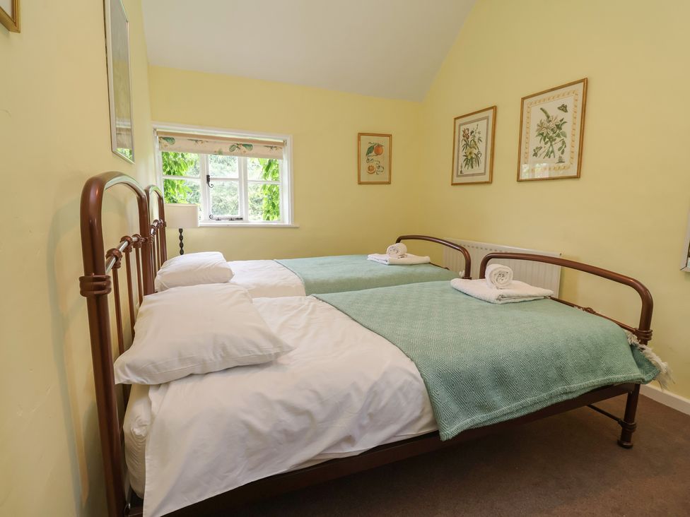 A bedroom with two beds and a window at Wolvesacre Mill Cottage in Agden near Whitchurch