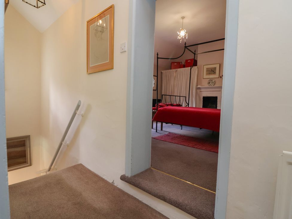 A view from a hallway into a bedroom with a bed and a chandelier at Wolvesacre Mill Cottage Agden near Whitchurch