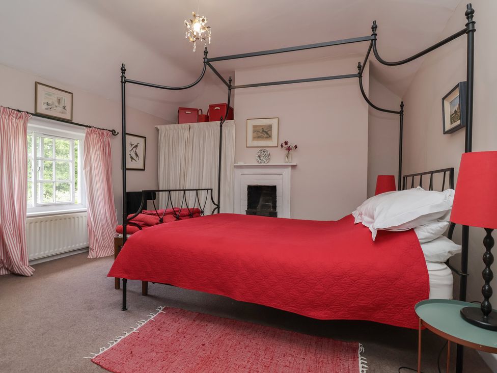 A bedroom with a red bed and curtains at Wolvesacre Mill Cottage Agden near Whitchurch