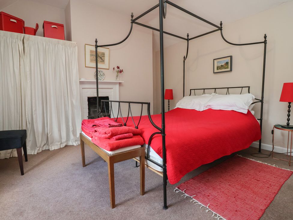 A bedroom with a four-poster bed and red bedspread at Wolvesacre Mill Cottage in Agden near Whitchurch