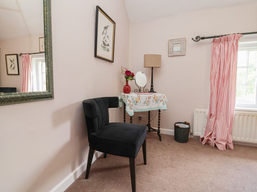 A bedroom with a chair and a table at Wolvesacre Mill Cottage Agden near Whitchurch