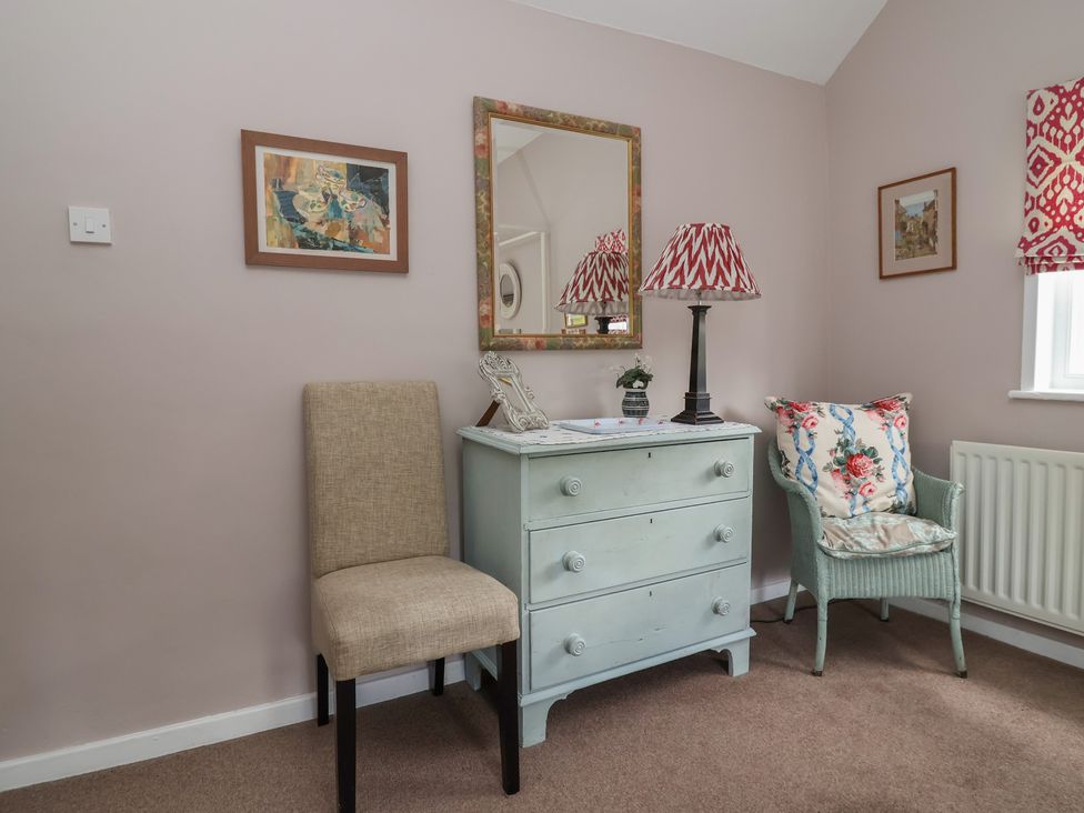 A bedroom with a dresser and chair at Wolvesacre Mill Cottage Agden near Whitchurch