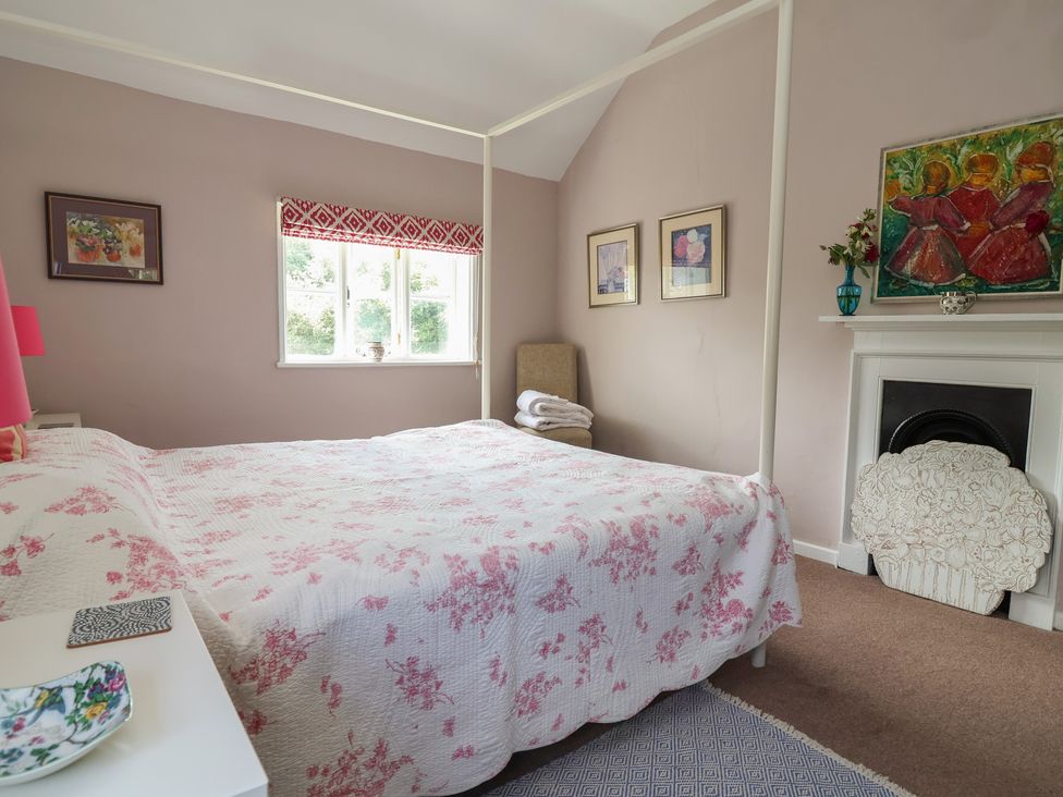 A bedroom with a bed and paintings at Wolvesacre Mill Cottage Agden near Whitchurch