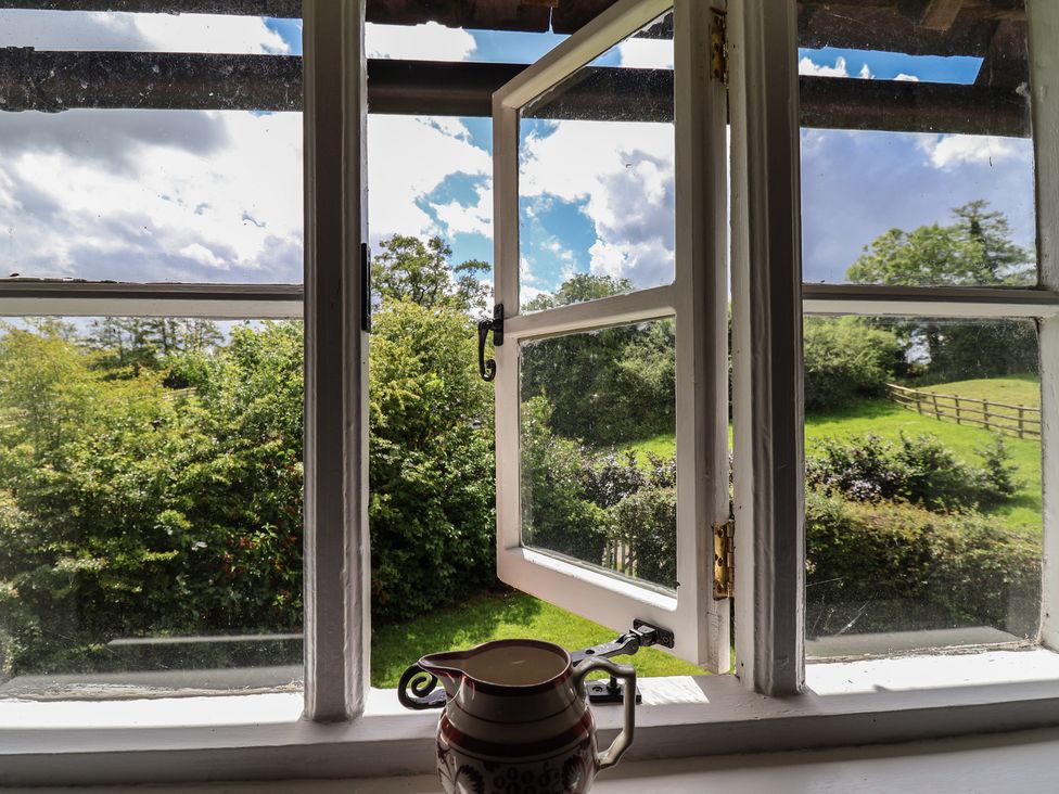 A view from a window with a pot and garden outside at Wolvesacre Mill Cottage in Agden near Whitchurch