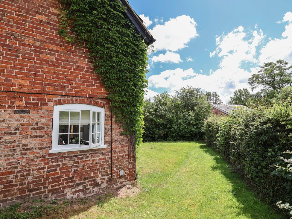 An outdoor area with a brick wall and a window at Wolvesacre Mill Cottage Agden near Whitchurch
