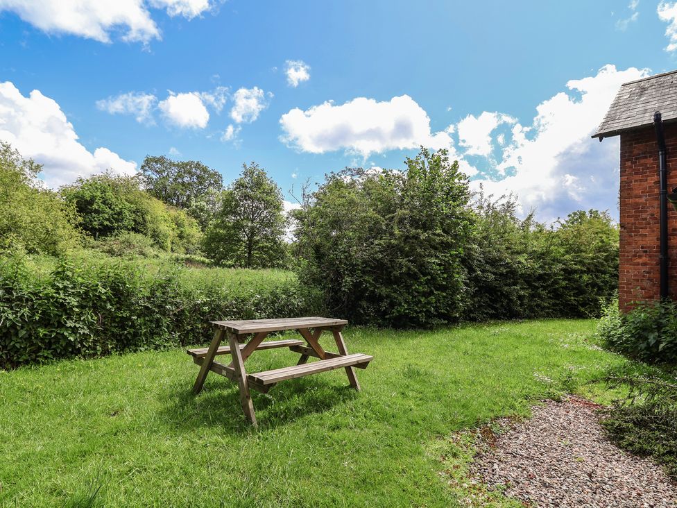 A garden with a picnic table and grass at Wolvesacre Mill Cottage in Agden near Whitchurch