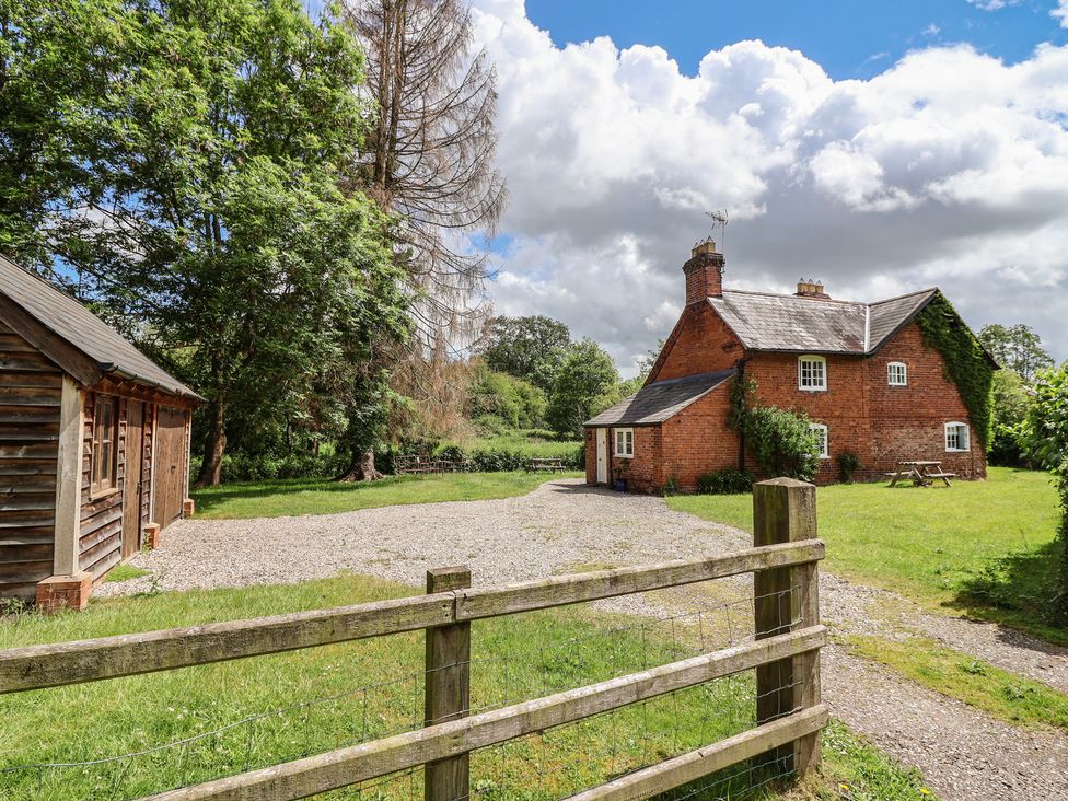 A cottage and a wooden shed outside at Wolvesacre Mill Cottage Agden near Whitchurch
