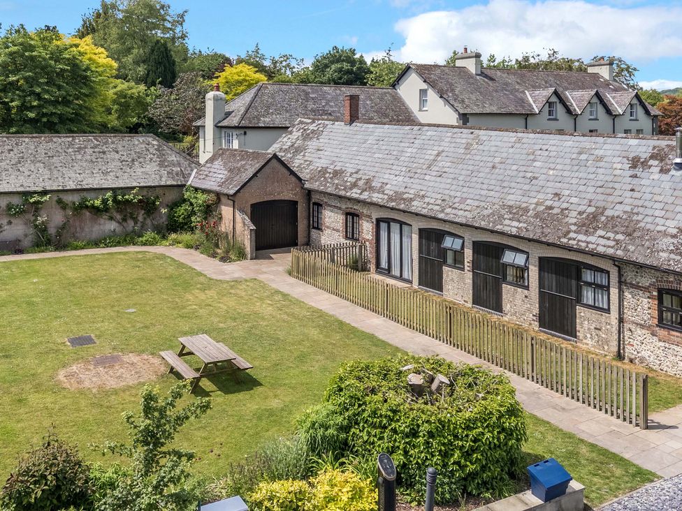 An outdoor area with buildings and a table at The Old Stables in Winterborne Stickland