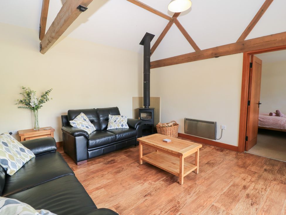 A living room with a sofa, coffee table, and stove at Corner Barn in Winterborne Stickland