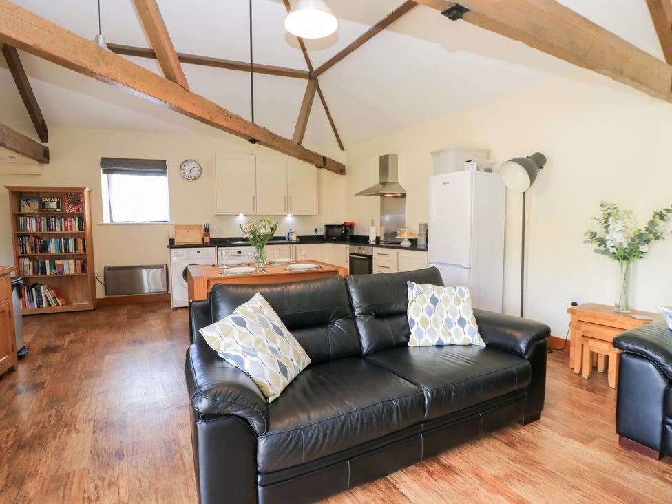 A living room with a sofa and kitchen units at Corner Barn Winterborne Stickland
