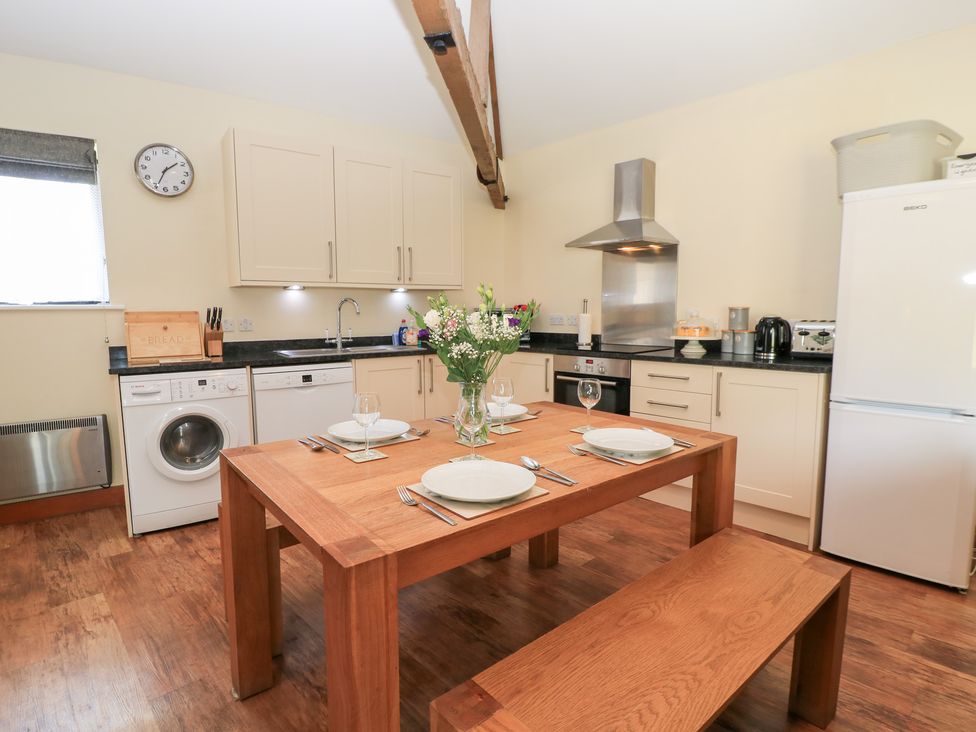 A kitchen with a dining table and appliances at Corner Barn Winterborne Stickland