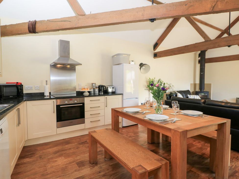 A kitchen with a dining table and benches at Corner Barn Winterborne Stickland