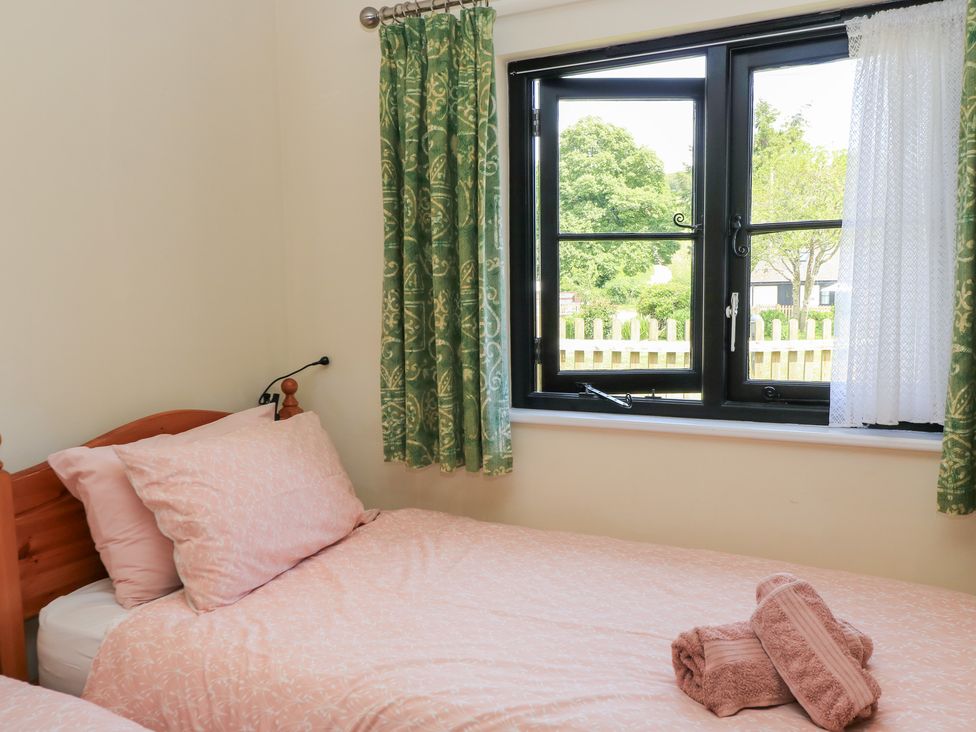 A bedroom with two beds and a window at Corner Barn in Winterborne Stickland