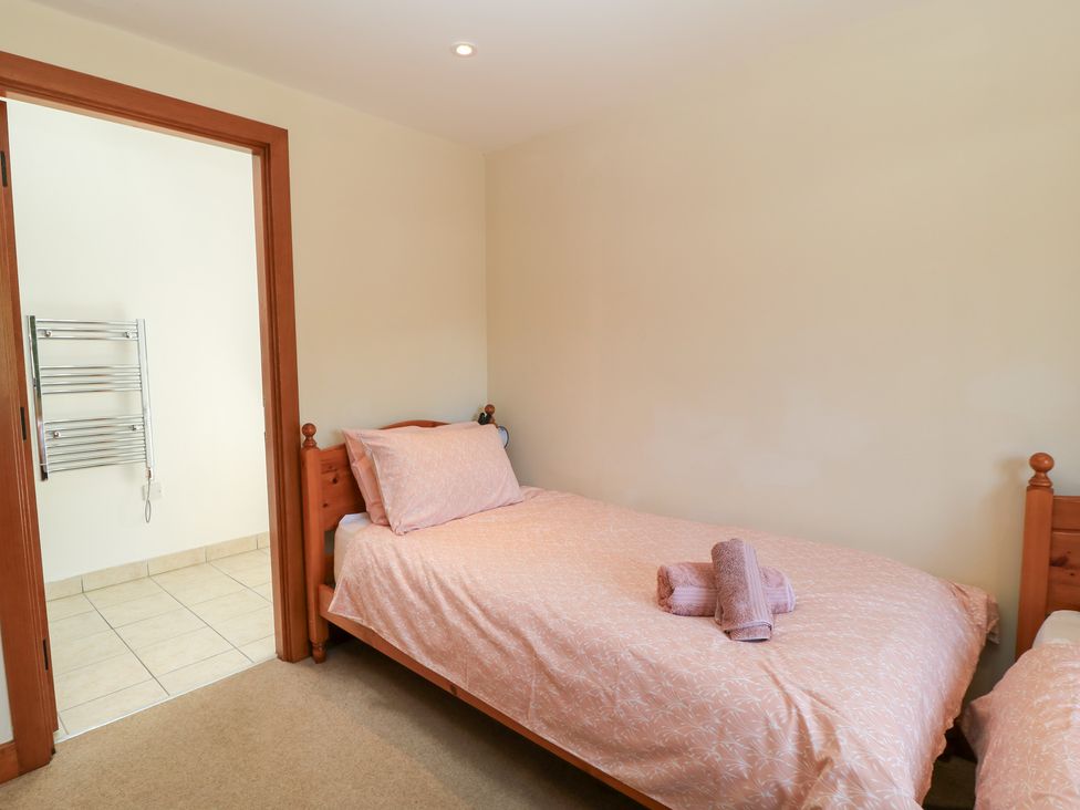 A bedroom with two beds and a heated towel rail at Corner Barn in Winterborne Stickland