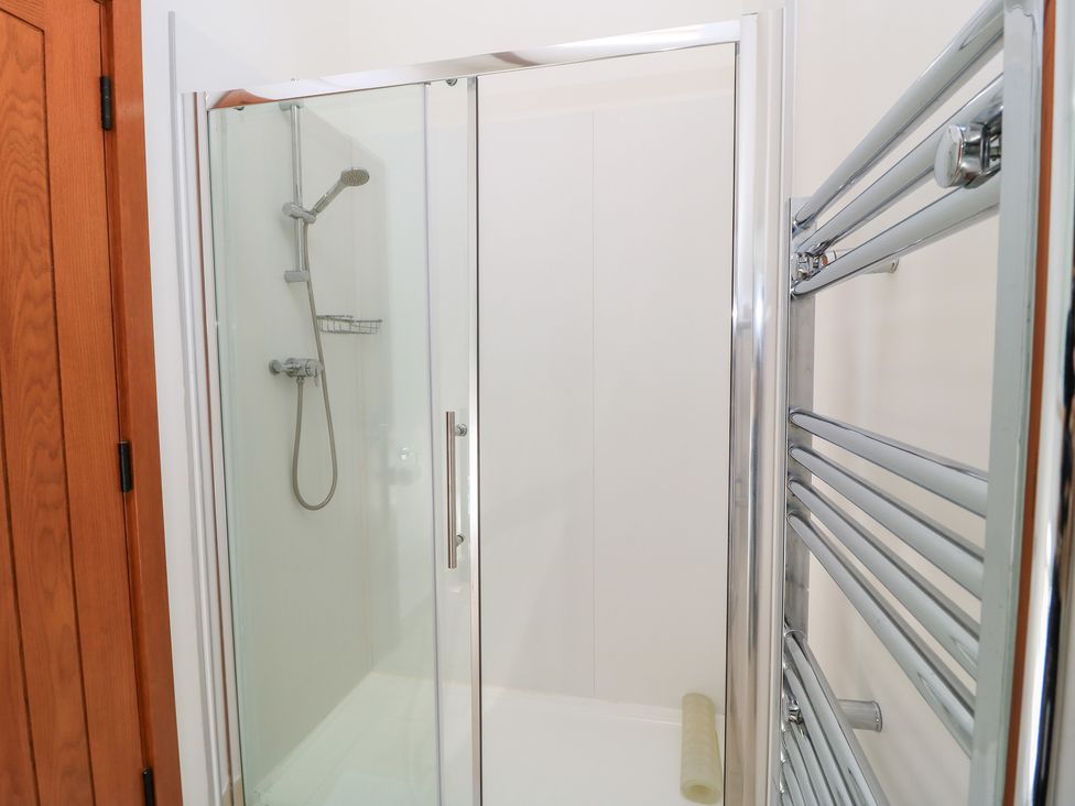A shower with glass door and towel rail at Corner Barn Winterborne Stickland