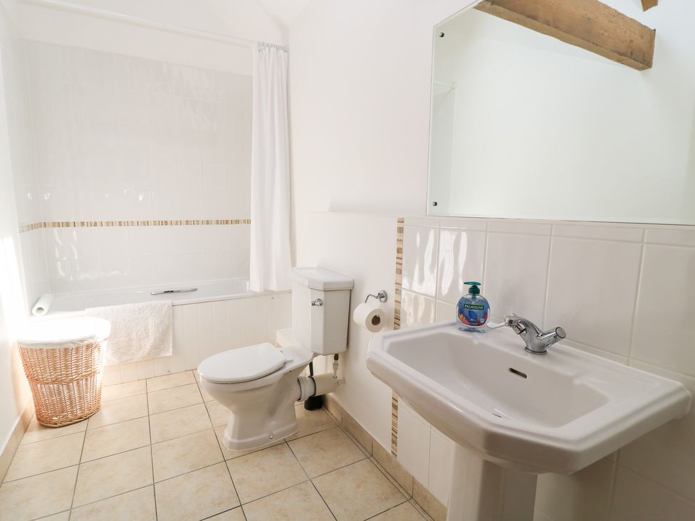 A bathroom with a bathtub, toilet, and sink at Corner Barn Winterborne Stickland
