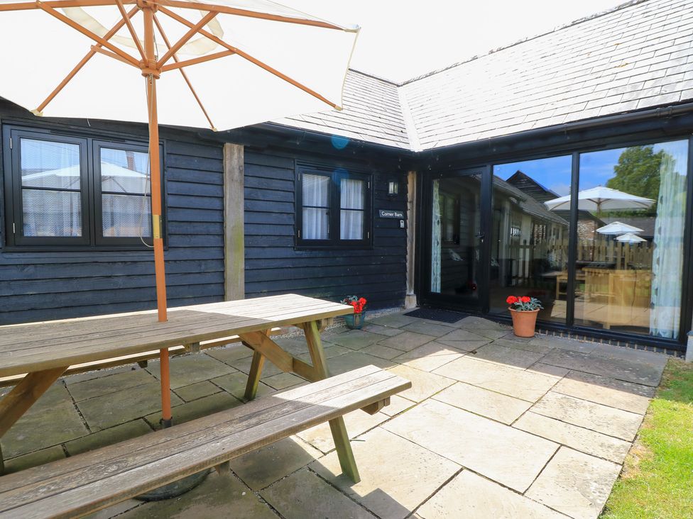 An outdoor seating area with a table and umbrella at Corner Barn Winterborne Stickland